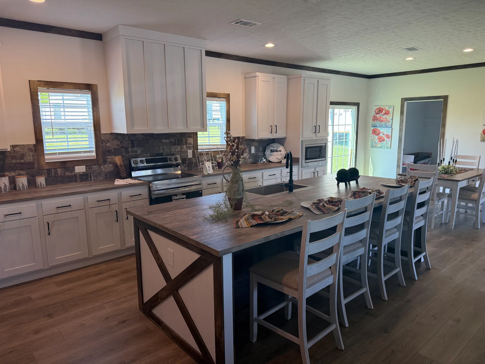 Open kitchen in a model home with a large wood island, farmhouse-style seating and white cabinets